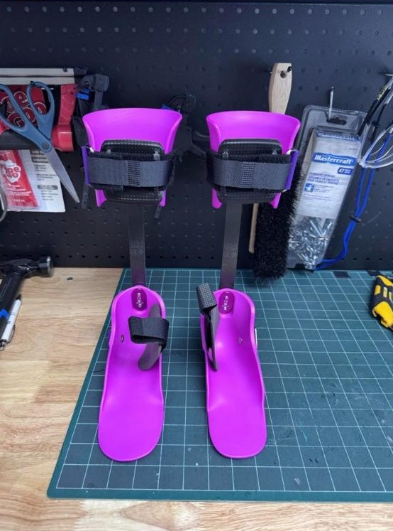 Pair of purple kids ankle foot orthoses with a flexible strut behind the leg, made by WingTek