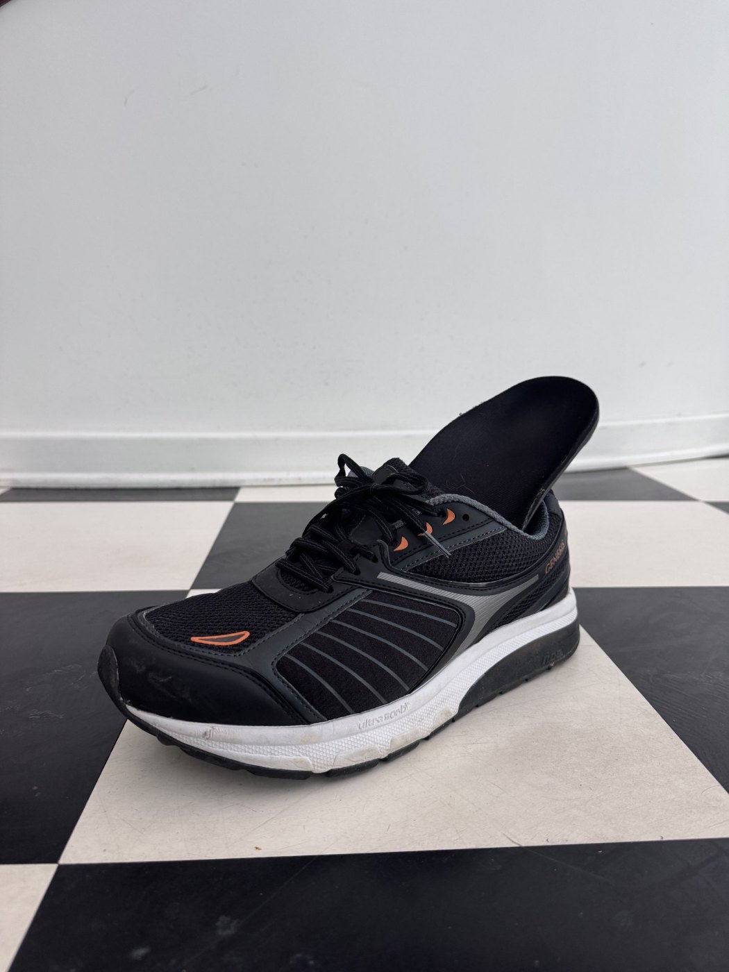 Custom foot orthotic tucked into a black supportive walking shoe