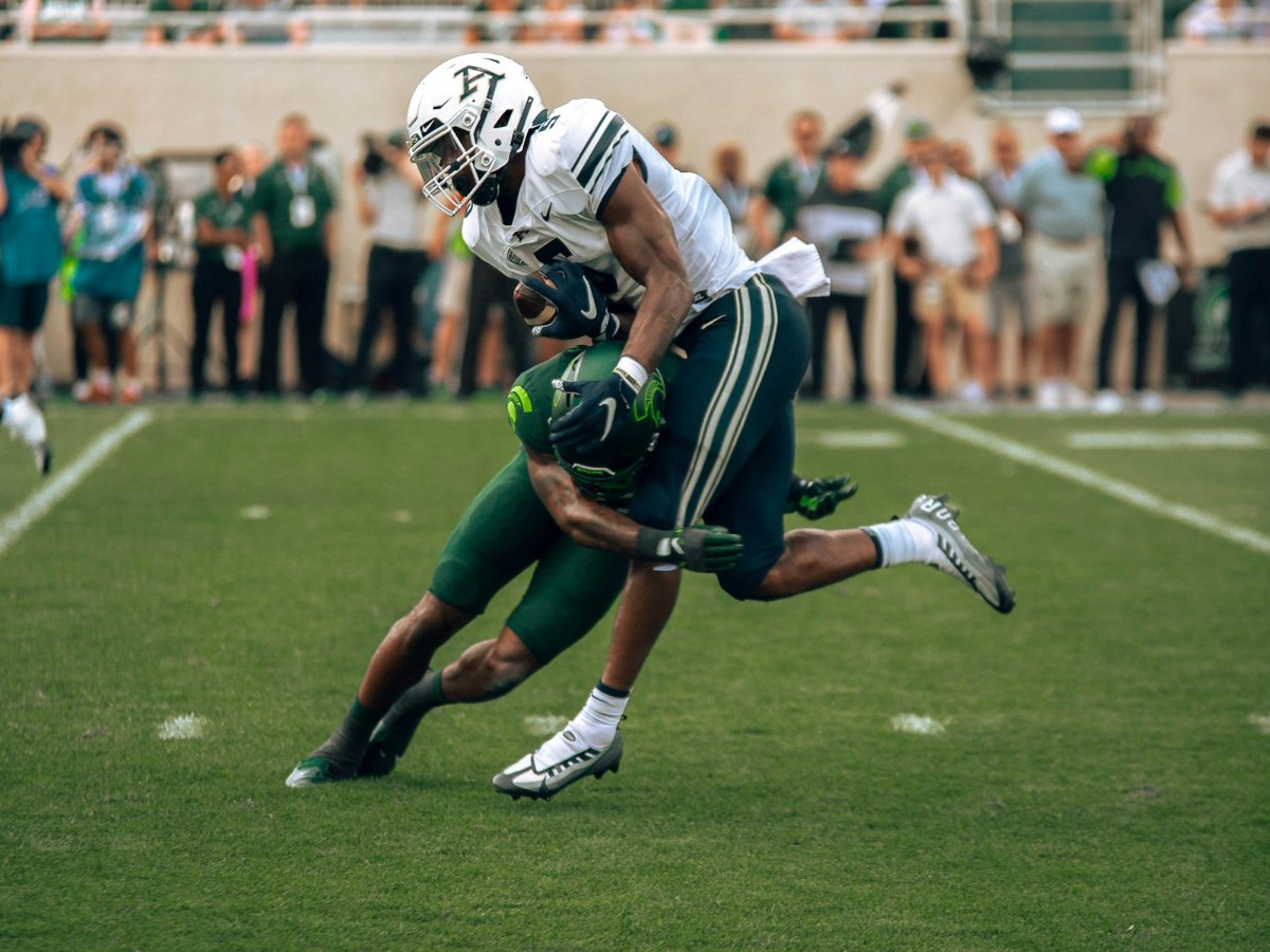 Two football players collide in a tackle on the field.