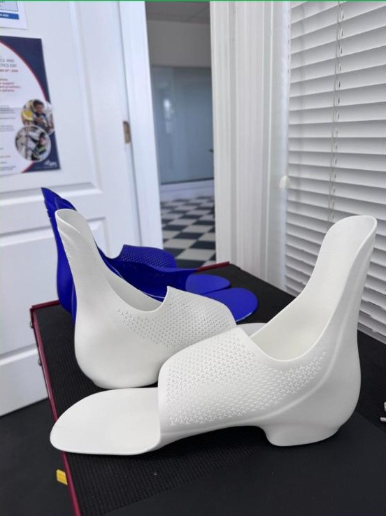Pair of white custom 3D printed supramalleolar orthoses (SMOs) with air holes, made by WingTek