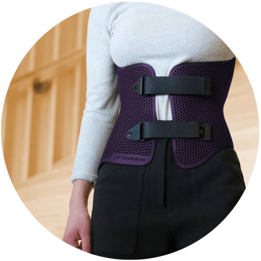 Person wearing a purple 3D printed scoliosis brace with a honeycomb pattern over a sweater