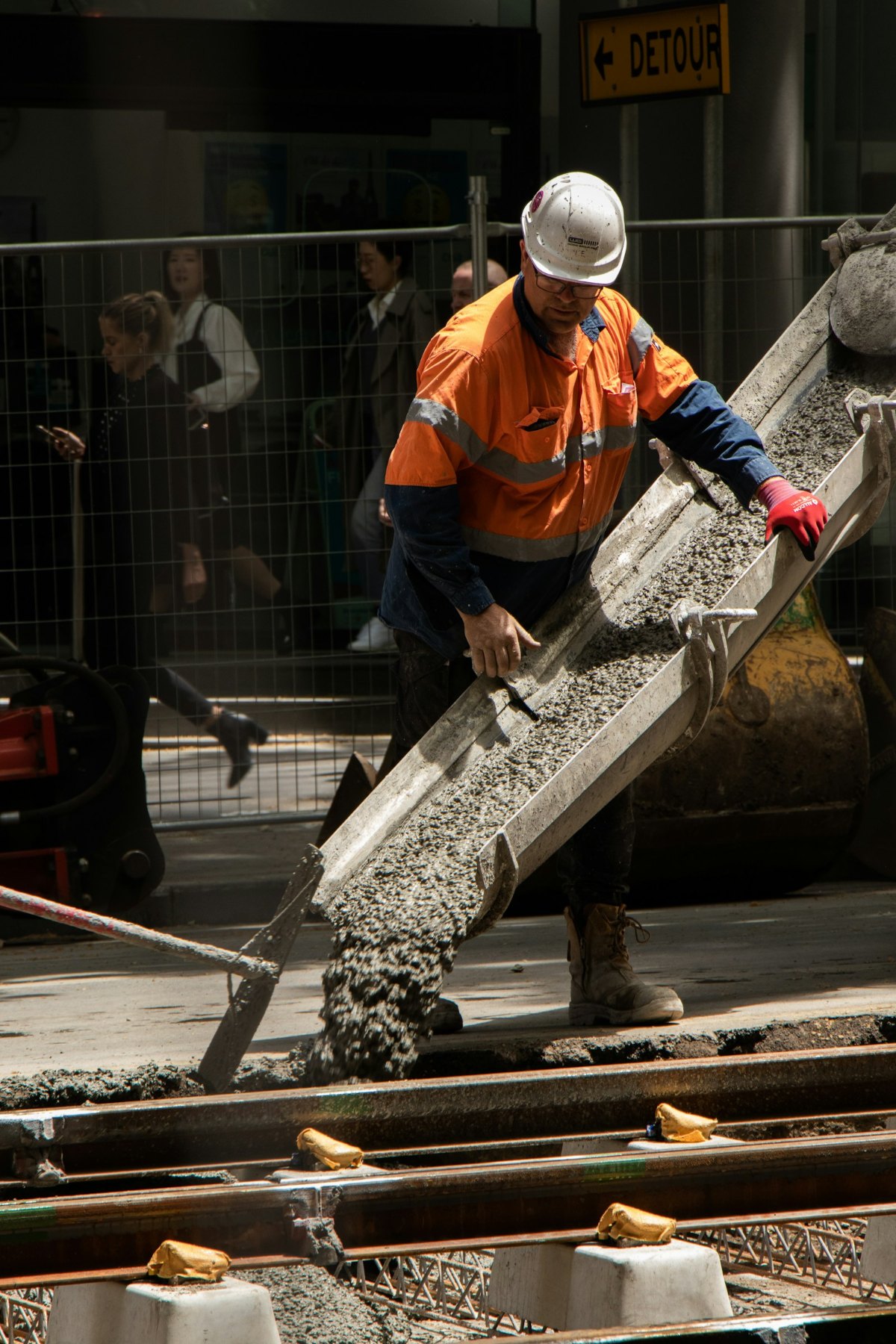 Construction worker in safety boots pouring concrete on a job site